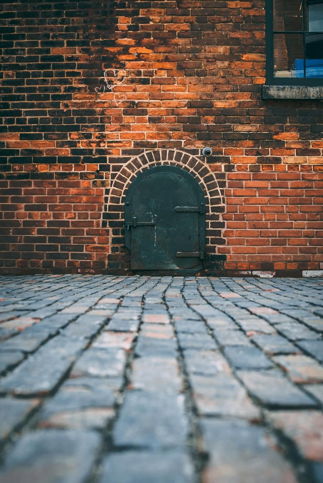 Arched green door set in a brick wall